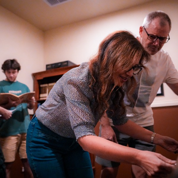 A woman unlocking a desk while people search for clues
