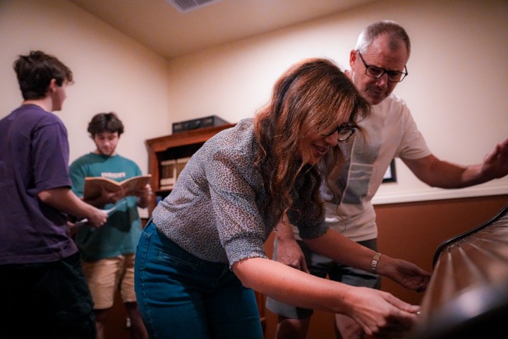 A woman unlocking a desk while people search for clues