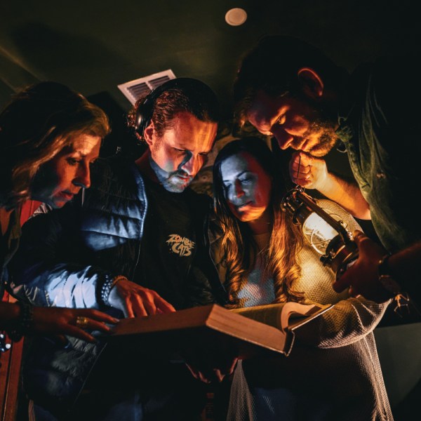 a group of people in a dark room looking at a book